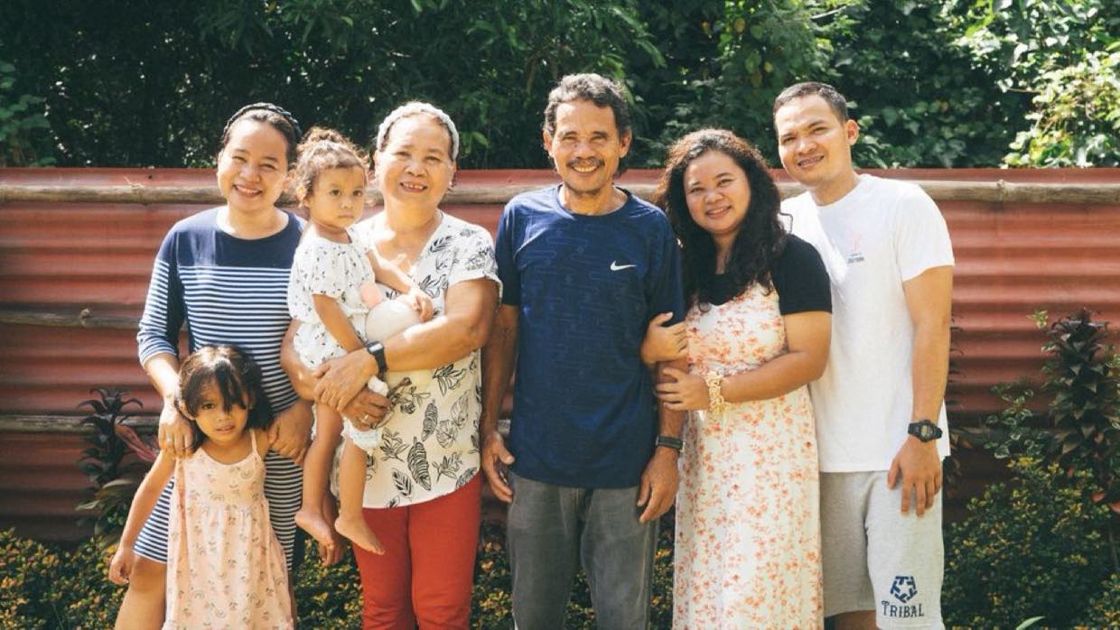 A multi-generational Filipino family standing together outside their home.